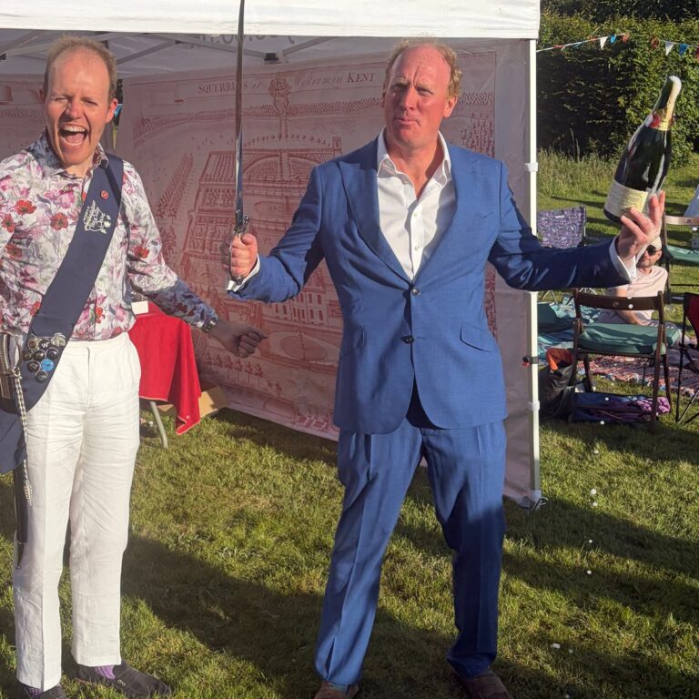 Man in a blue suit raising a sabre outdoors